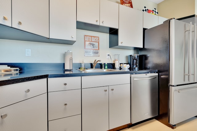 kitchen featuring appliances with stainless steel finishes, white cabinetry, sink, and light tile floors