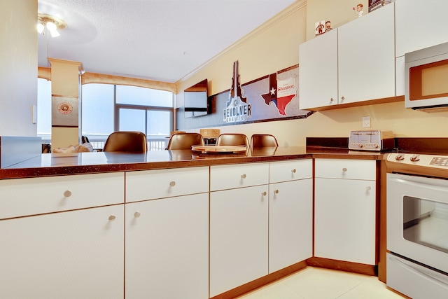 kitchen with white cabinets, ceiling fan, stove, and light tile flooring