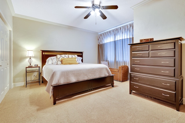 carpeted bedroom with a closet, ceiling fan, and crown molding