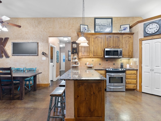 kitchen featuring decorative light fixtures, appliances with stainless steel finishes, a kitchen breakfast bar, dark stone countertops, and decorative backsplash