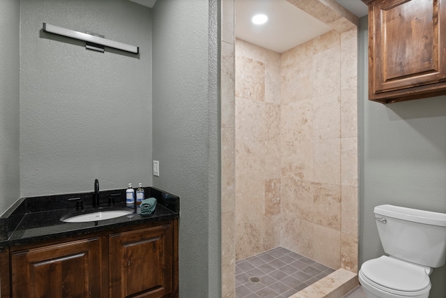 bathroom with tiled shower, vanity, and toilet