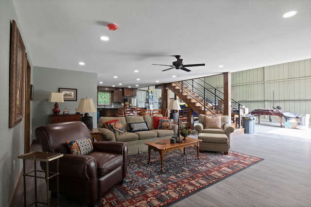 living room with wood-type flooring, ceiling fan, and a textured ceiling