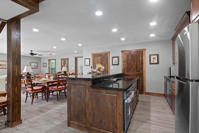 kitchen featuring light hardwood / wood-style flooring, dark stone counters, stainless steel refrigerator, dark brown cabinetry, and ceiling fan