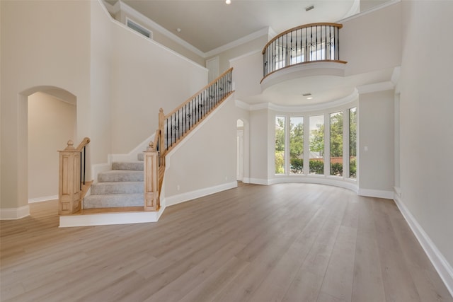 foyer entrance featuring a notable chandelier, crown molding, light wood-type flooring, french doors, and ornate columns