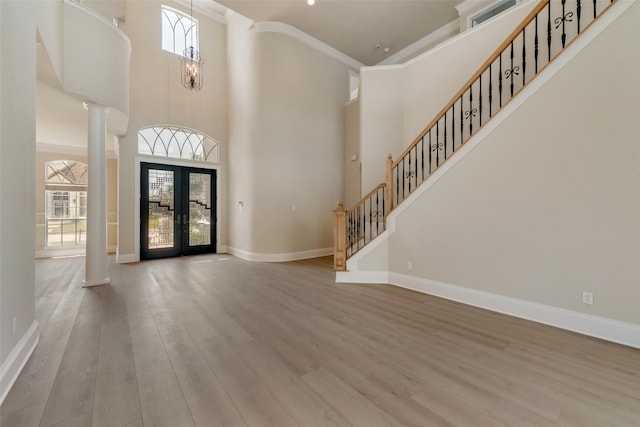 entryway with wood-type flooring, crown molding, and a high ceiling