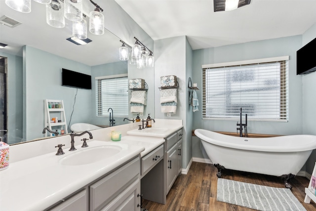 bathroom with a bathing tub, vanity, a healthy amount of sunlight, and hardwood / wood-style flooring