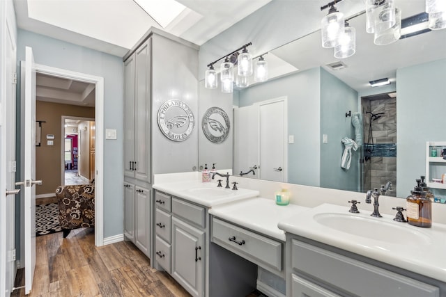 bathroom featuring wood-type flooring, vanity, and a tile shower