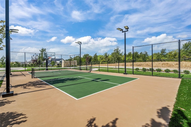 view of tennis court featuring community basketball court and fence