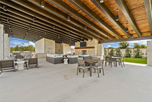 view of patio featuring an outdoor living space with a fireplace, fence, and outdoor dining area