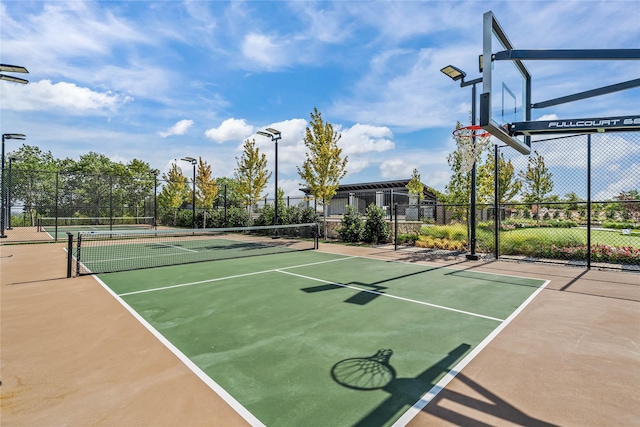 view of tennis court featuring community basketball court and fence