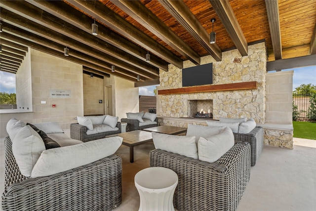 living area featuring lofted ceiling with beams, an outdoor stone fireplace, and wood ceiling