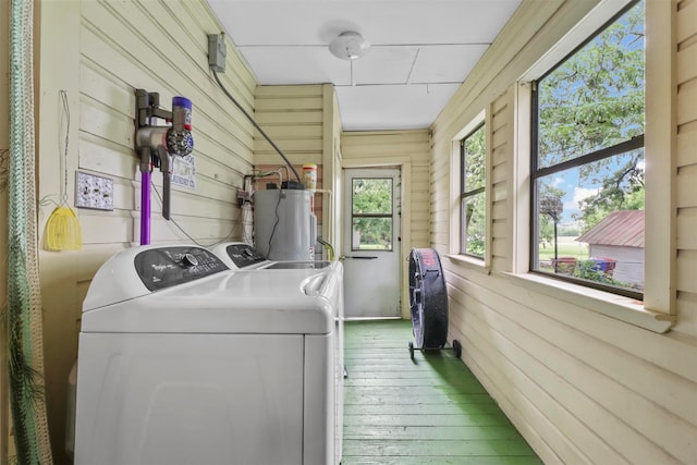 laundry area with washer and clothes dryer, plenty of natural light, wooden walls, and water heater