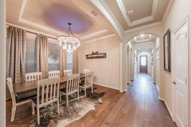 dining room featuring hardwood / wood-style flooring, a notable chandelier, crown molding, and a tray ceiling