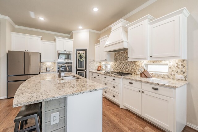 kitchen featuring white cabinetry, sink, stainless steel appliances, a kitchen island with sink, and custom exhaust hood