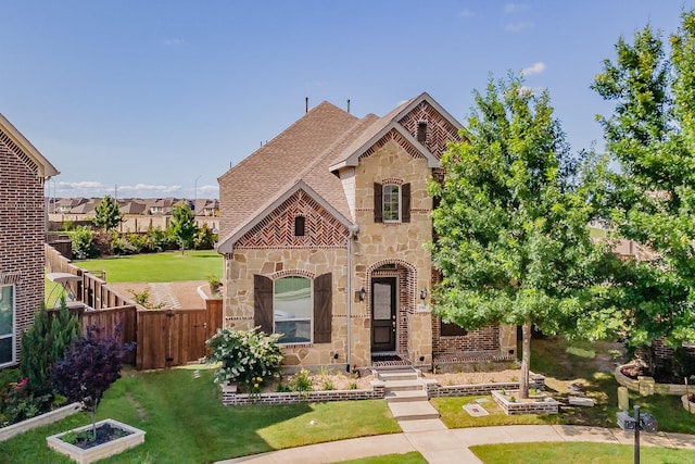 view of front of property featuring brick siding, a front yard, fence, and stone siding