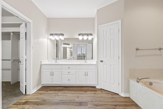 bathroom featuring hardwood / wood-style flooring, dual sinks, a tub, and vanity with extensive cabinet space