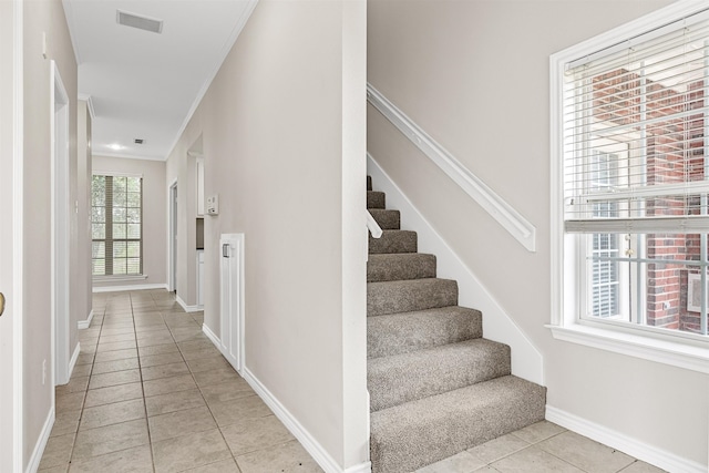 stairway featuring crown molding and light tile floors