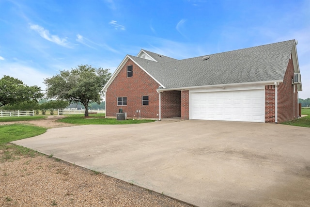 view of side of property featuring a garage, central AC unit, and a lawn