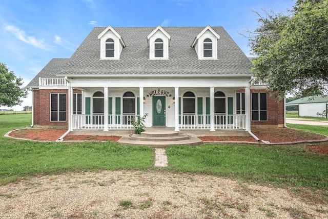 cape cod-style house featuring covered porch and a front lawn