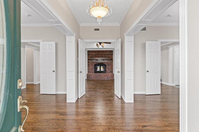 entryway with ornamental molding, a brick fireplace, and dark hardwood / wood-style flooring