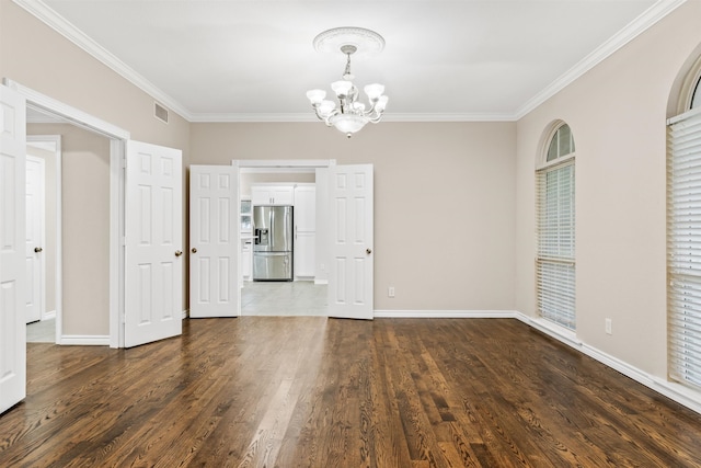 spare room featuring a chandelier, ornamental molding, and wood-type flooring