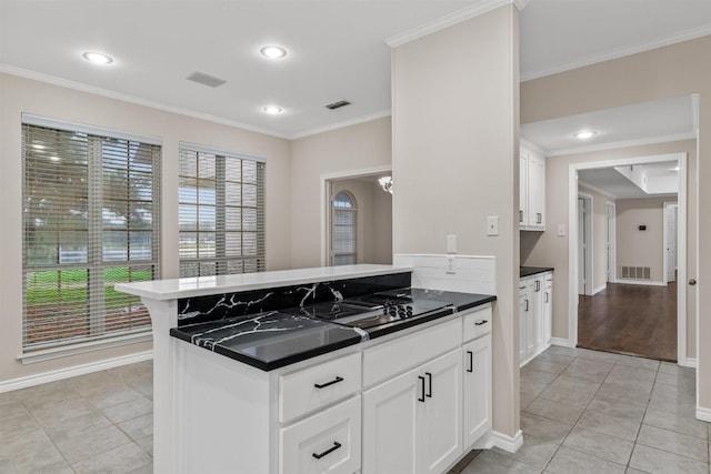 kitchen with crown molding, kitchen peninsula, light tile patterned floors, and white cabinets