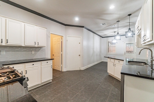 kitchen featuring backsplash, crown molding, sink, decorative light fixtures, and white cabinets