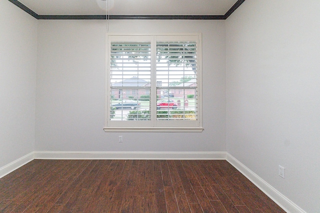 spare room featuring a healthy amount of sunlight, crown molding, and dark wood-type flooring