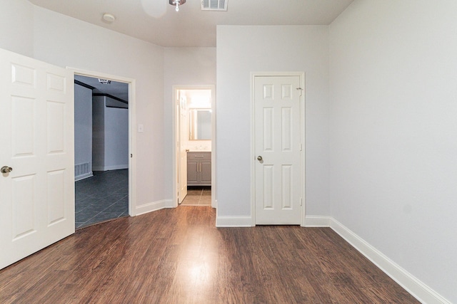 unfurnished bedroom with dark hardwood / wood-style flooring and ensuite bath