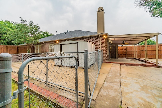 view of gate featuring a storage shed and a patio