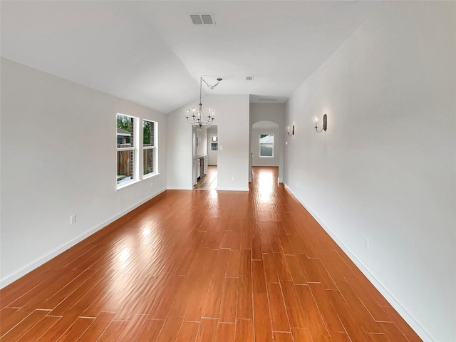 unfurnished living room with an inviting chandelier, hardwood / wood-style floors, and lofted ceiling