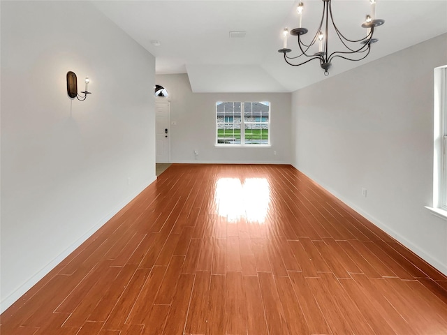 spare room with hardwood / wood-style flooring and a chandelier