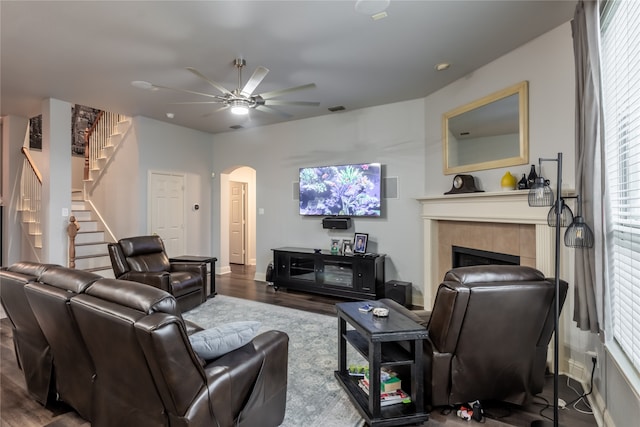 living room with ceiling fan, wood-type flooring, and a tile fireplace