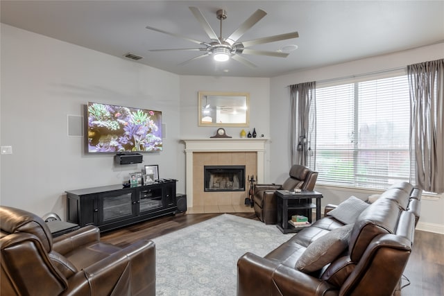 living room with ceiling fan, a tiled fireplace, and dark hardwood / wood-style flooring