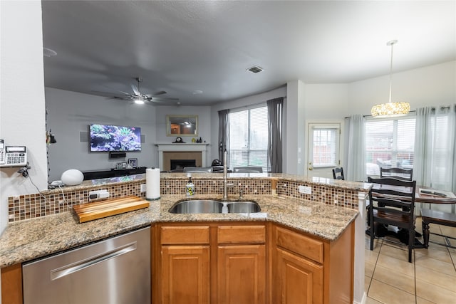 kitchen featuring decorative backsplash, stainless steel dishwasher, light stone countertops, ceiling fan with notable chandelier, and light tile patterned floors