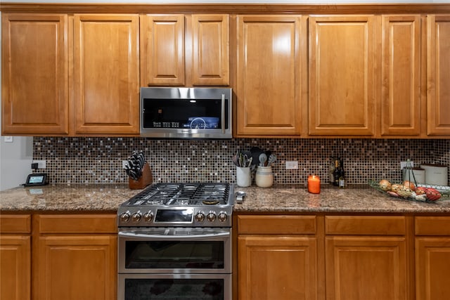 kitchen featuring tasteful backsplash, appliances with stainless steel finishes, and dark stone counters