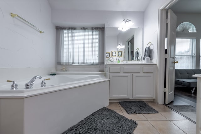 bathroom featuring a wealth of natural light, a bathing tub, tile patterned flooring, and vanity