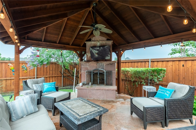 view of patio featuring ceiling fan, an outdoor living space with a fireplace, and a gazebo