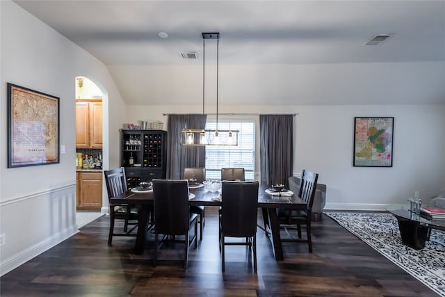 dining room featuring a notable chandelier, vaulted ceiling, and dark hardwood / wood-style floors