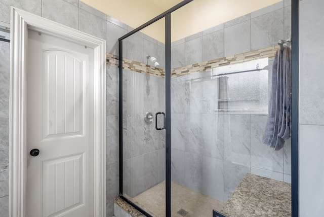 bathroom with a shower with shower door and tile walls