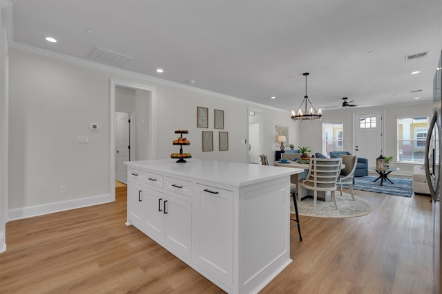 kitchen with light hardwood / wood-style flooring, decorative light fixtures, ceiling fan with notable chandelier, a center island, and white cabinetry