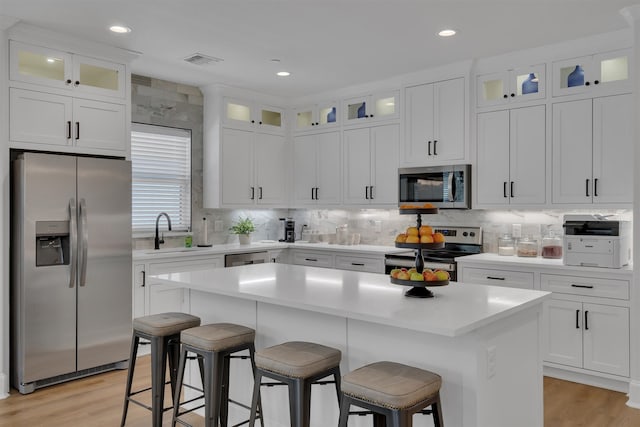 kitchen with appliances with stainless steel finishes, sink, a center island, and white cabinetry