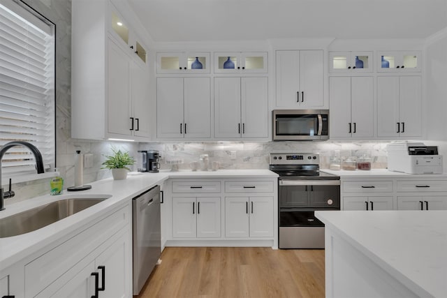 kitchen with stainless steel appliances, white cabinets, sink, and light wood-type flooring