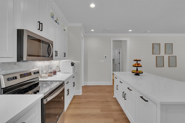 kitchen with stainless steel appliances, white cabinetry, light hardwood / wood-style floors, and backsplash