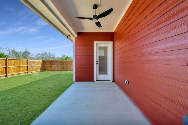 view of exterior entry featuring ceiling fan, a lawn, and a patio