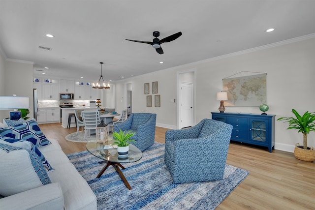 living room featuring ornamental molding, ceiling fan with notable chandelier, and light hardwood / wood-style flooring