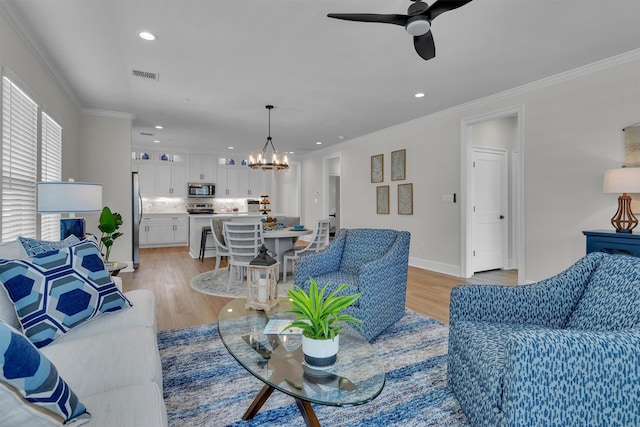 living room with ceiling fan with notable chandelier, crown molding, and light wood-type flooring