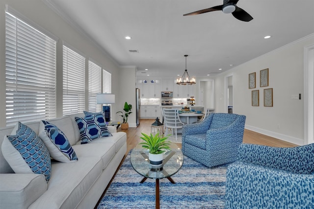 living room featuring crown molding, light wood-type flooring, and ceiling fan with notable chandelier