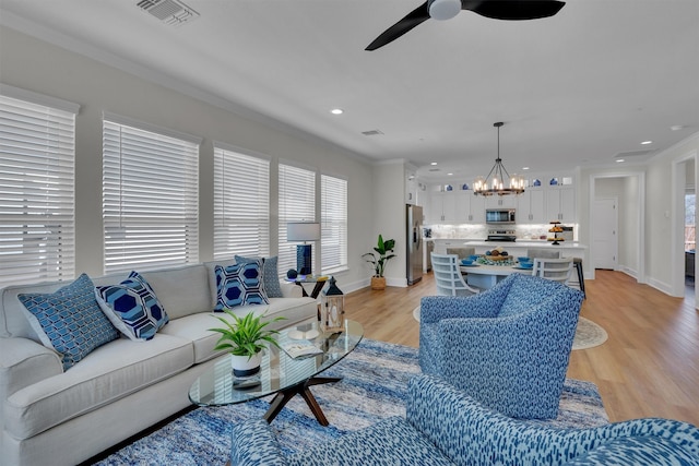 living room featuring light hardwood / wood-style flooring and ceiling fan with notable chandelier