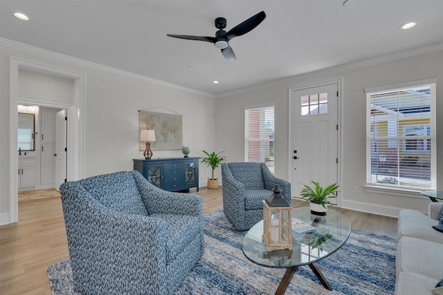 living room with ceiling fan, light wood-type flooring, and ornamental molding